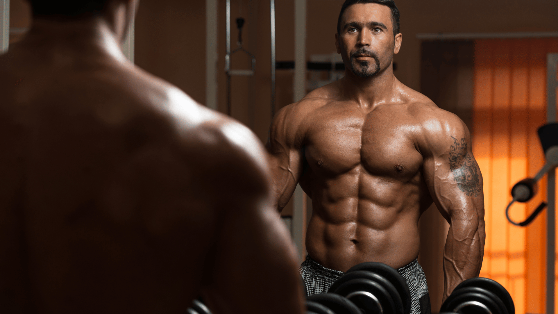 Homem na academia olhando a sua massa muscular